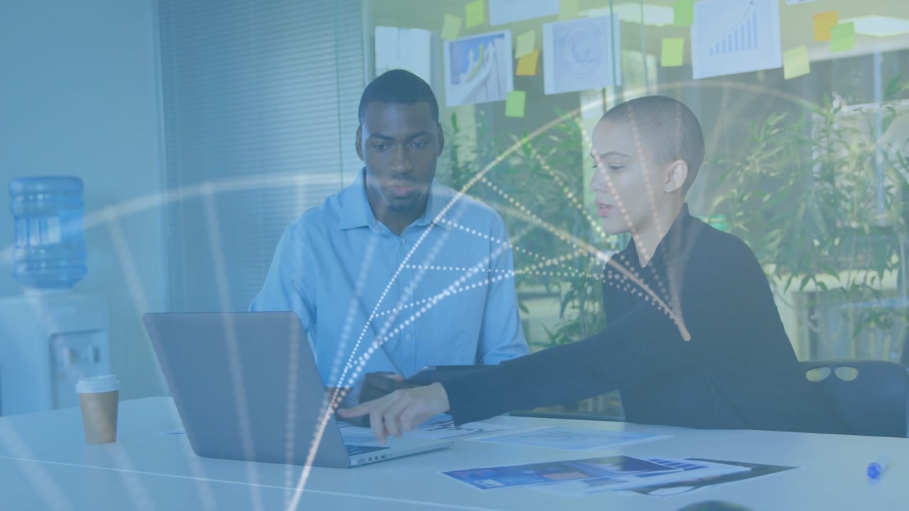 Man holding tablet while woman pointing and typing at laptop, business arc dotted overlays evolving