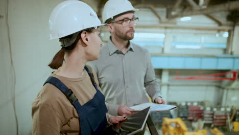 female and male engineers discussing industrial machinery in factory