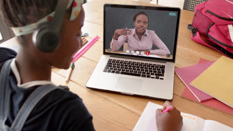 composición de una colegiala afroamericana en una computadora portátil aprendiendo en línea con una maestra