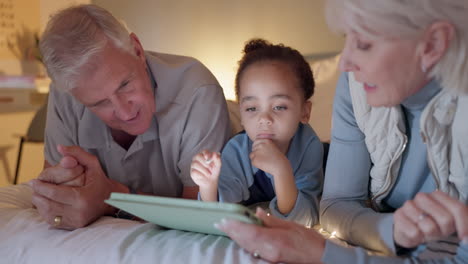 abuelos, niño y tableta en la cama