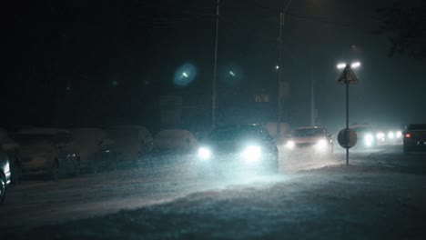 Cars-driving-in-the-city-on-a-frosty-winter-night-during-a-blizzard,-super-slow-motion