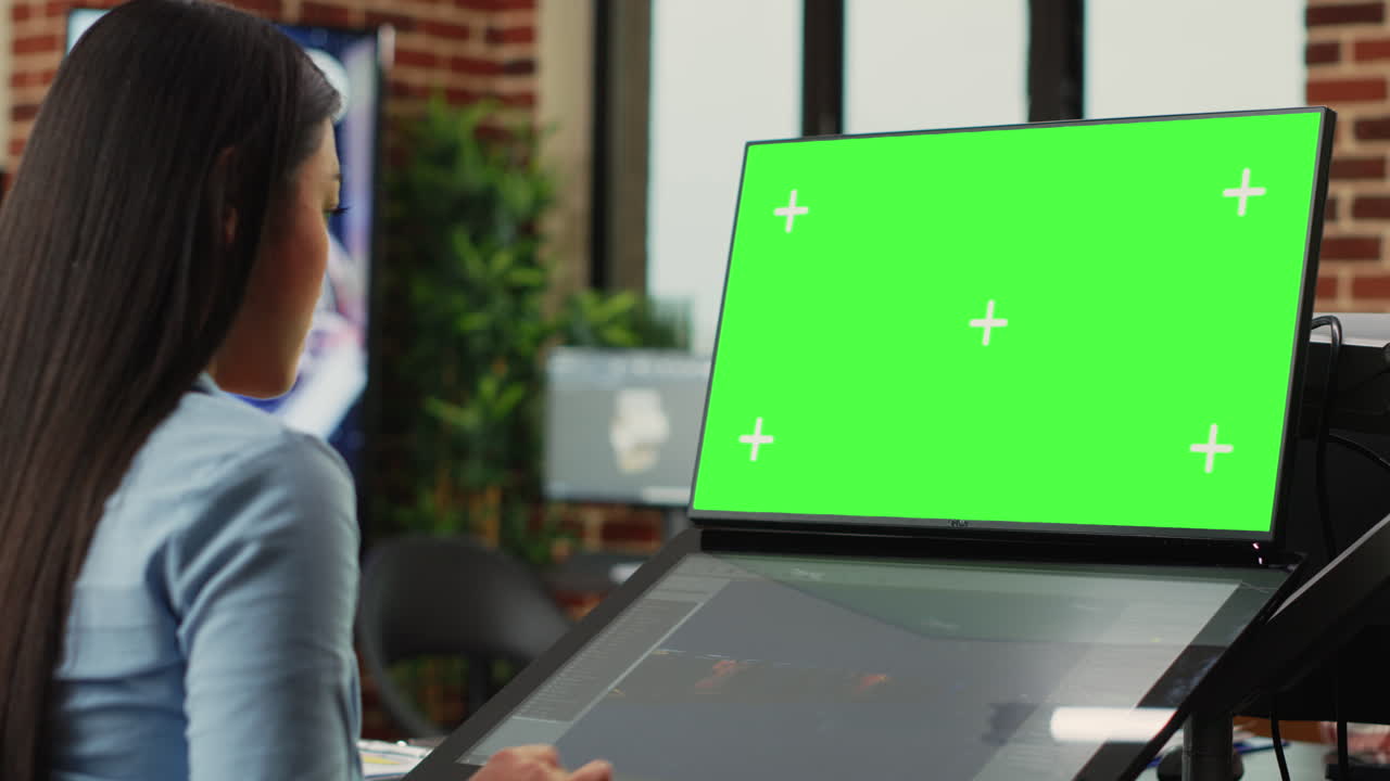 Asian woman using game developing software and greenscreen display