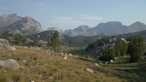 an open field in wind river wilderness with rugged rocky terrain, hills, and distant mountains