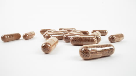 scattered herbal capsules with natural fillings on a clean white backdrop