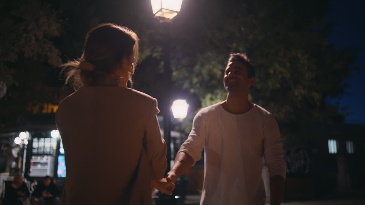 Dating couple embracing evening city. Happy man spinning affectionate woman