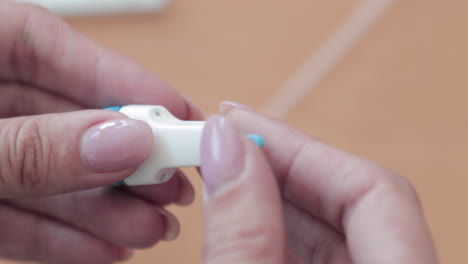 woman's finger firmly pushing and removing the cap of the lancet stick - covid-19 antibody test kit - closeup, slow motion