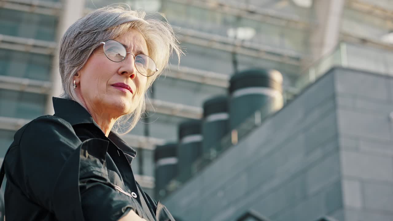 Urban portrait of a mature serious female manager. Middle-aged gray-haired lady. Slow motion
