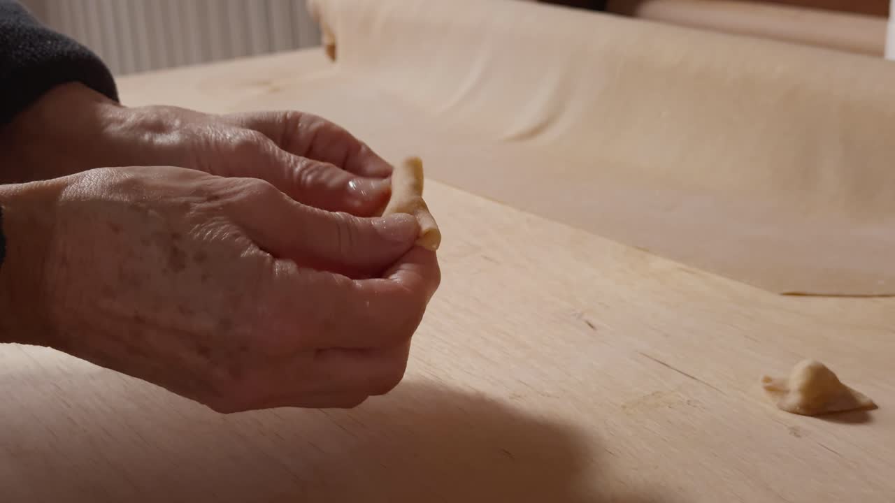 Elderly hands gently folding filled pasta on a wooden surface, highlighting the precision of homemade preparation