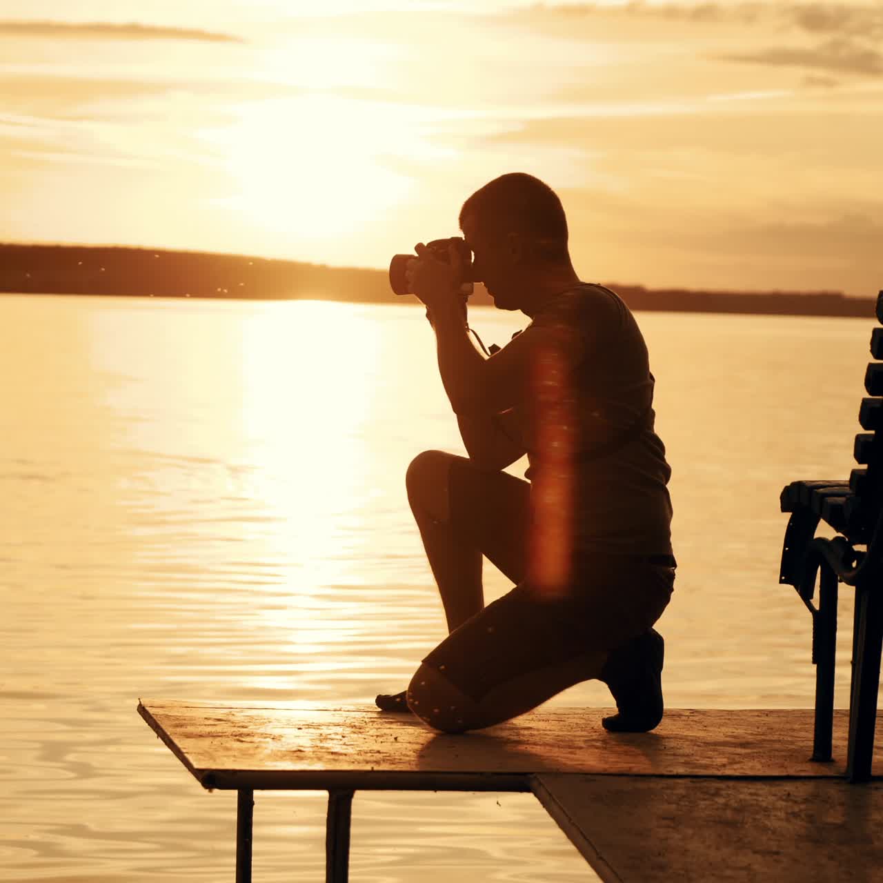 Photographer taking picture of landscape during sunset. Silhouette of people swimming in the river at sunset