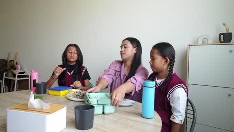 asian mother teaching her daughters to preparing lunchbox before go to school