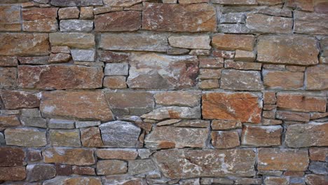 The-side-of-a-stone-built-cabin-lodge-showing-the-range-of-different-size-and-shaped-stones-used-to-build-the-space-with-sideways-movement-in-slow-motion