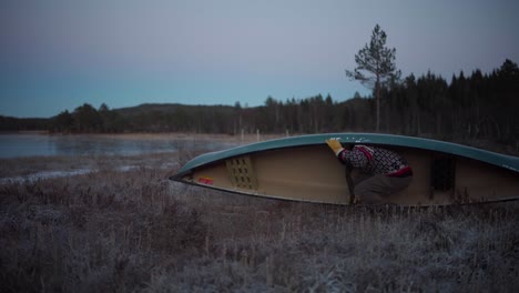 norwegian man lift and carry canoe boat on lake shore in norway