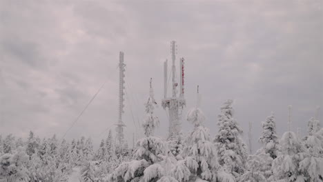 Torres-De-Antena-Con-Bosque-De-Coníferas-En-Primer-Plano-Cubierto-De-Nieve-En-La-Estación-De-Esquí-De-Mont-Orford-Durante-La-Temporada-De-Invierno-En-Quebec,-Canadá