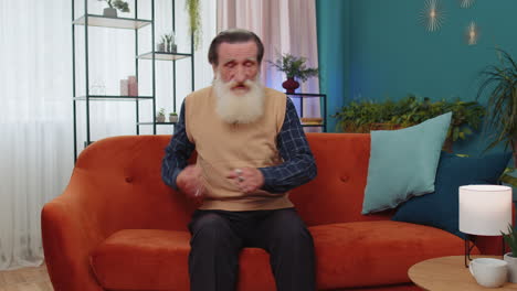 happy relaxed bearded grandfather man dancing listening favorite rock n roll music on home couch