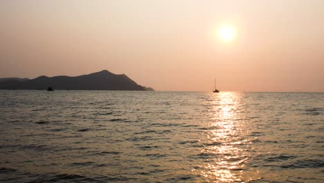 Stunning-Sunset-Over-Calm-Waters-with-a-Yacht-on-the-Horizon-in-Bangsaray-near-Pattaya,-Thailand