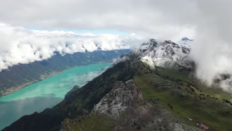 Drohnenaufnahme-Eines-Massiven-Und-Farbenfrohen-Flusses,-Der-Zwischen-Zwei-Epischen-Bergen-Mit-Wald,-Gras,-Grün-Und-Schnee-Auf-Den-Gipfeln-Fließt