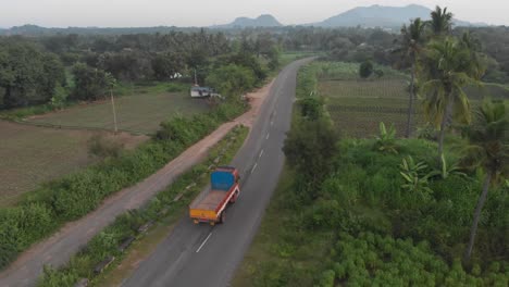 aerial tracking shot of driving truck on indian road during cloudy day