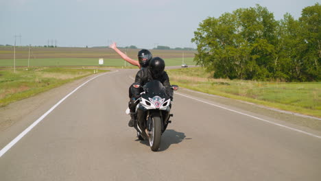 mujer con el brazo levantado disfruta de un paseo en motocicleta con su novio