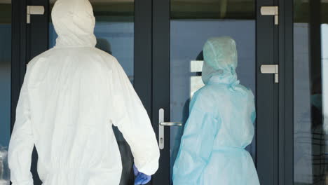 a group of medics in protective suits communicate with an elderly woman on the doorstep of her home