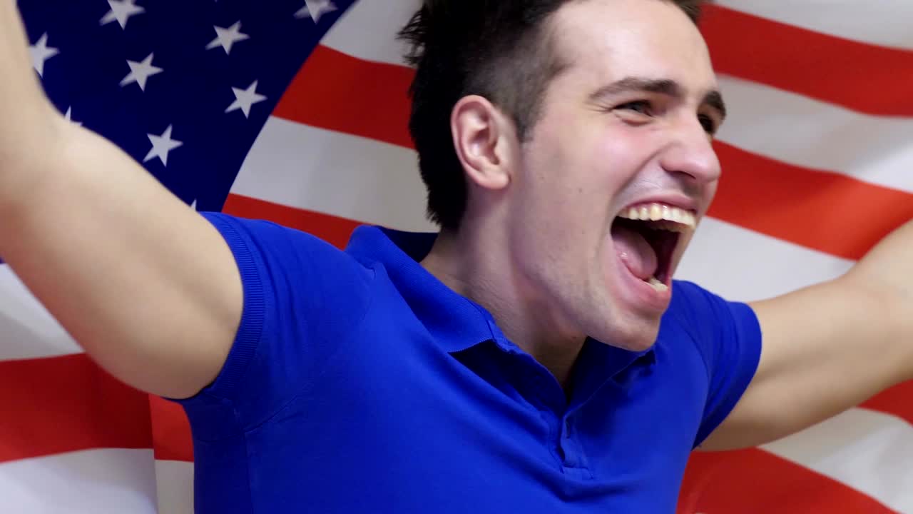 joven estadounidense celebrando mientras sostiene la bandera de américa en cámara lenta