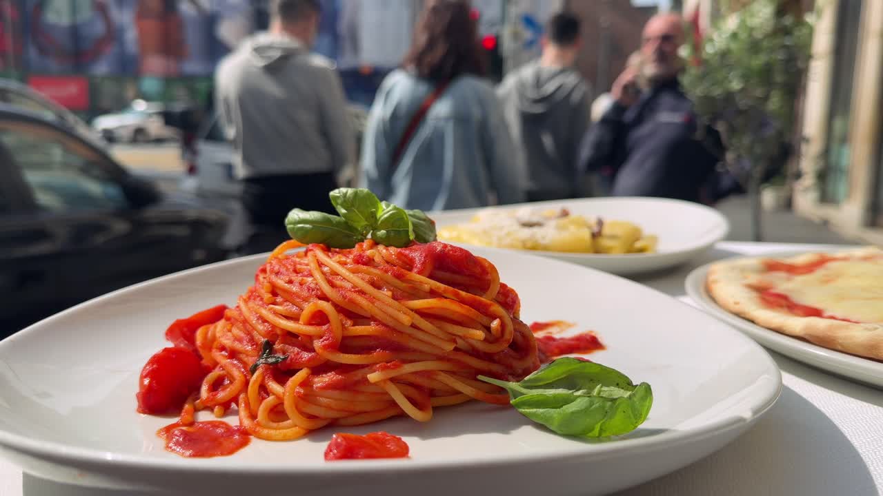 Läcker italiensk spaghetti, pizza och pastarätter på ett restaurangbord utomhus