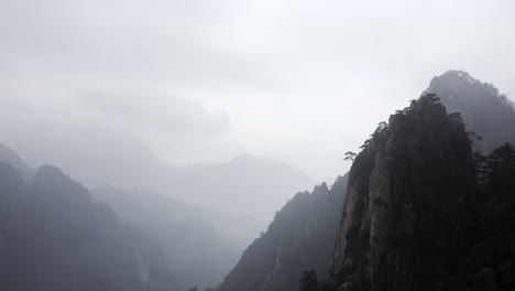 china mountain peak coming into focus over misty valley, aerial arc shot reveal