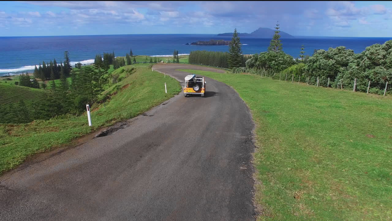 노르폴크를 가로질러 파도를 찾는 노란색 지프의 서프보드