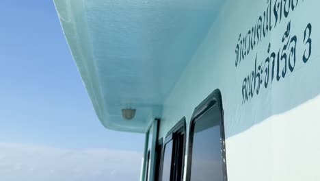 A detailed view of a boat's side with text, set against a clear blue sky.