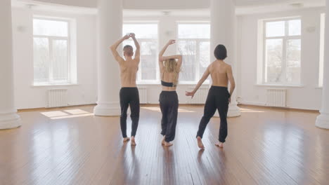 back view of three professional contemporary dancers training dance moves in the studio 1