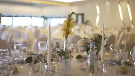 hand lighting tall white candles on a elegantly set table with flowers and glassware, preparing for a celebration