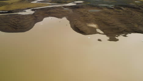 pan right aerial shot of cracked icebergs and shoreline of the fjallsárlón