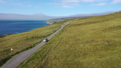 stunning drone shot following a car along a hilltop road beside the sea in north-east scotland near melvaig