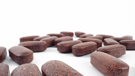 scattered herbal supplement pills on a clean white background with a soft focus