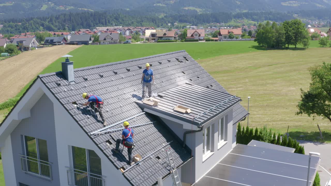 Ampio angolo di ripresa aerea di tre uomini che installano pannelli solari su una casa in Slovenia