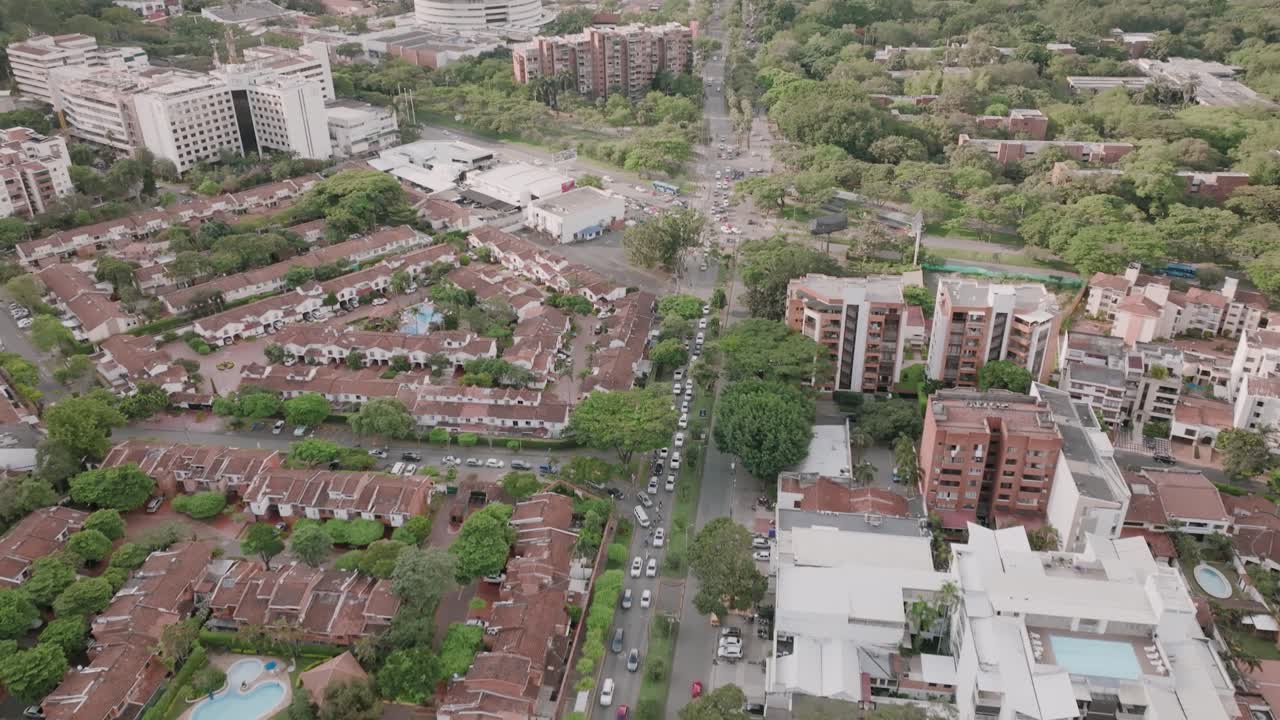 panorámica aérea lenta de tráfico, edificios de apartamentos y el centro comercial en los suburbios de cali, colombia