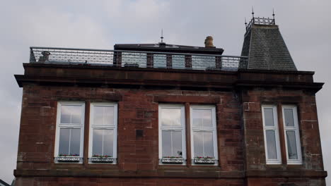 Red-brick-building-with-roof-and-windows-on-sunny-day-in-town