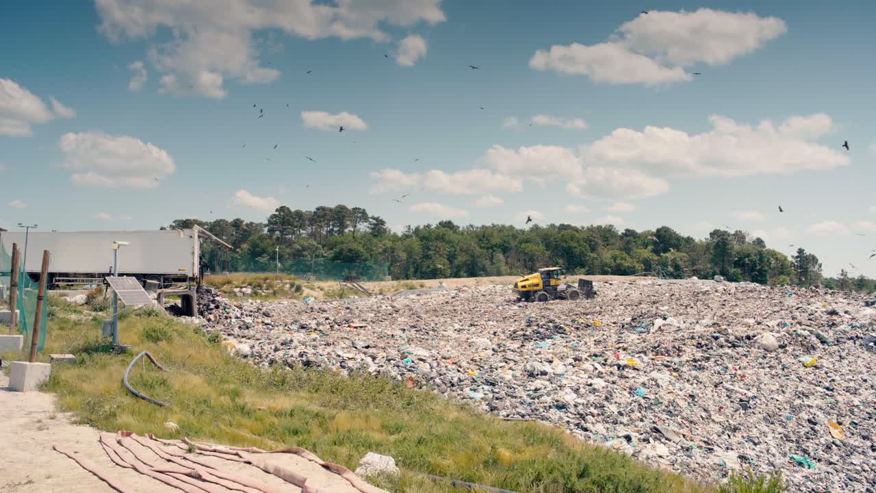 vista de gran ángulo de un camión empuja y compacta los residuos, que luego es arrojado por un semirremolque, creando una montaña de basura
