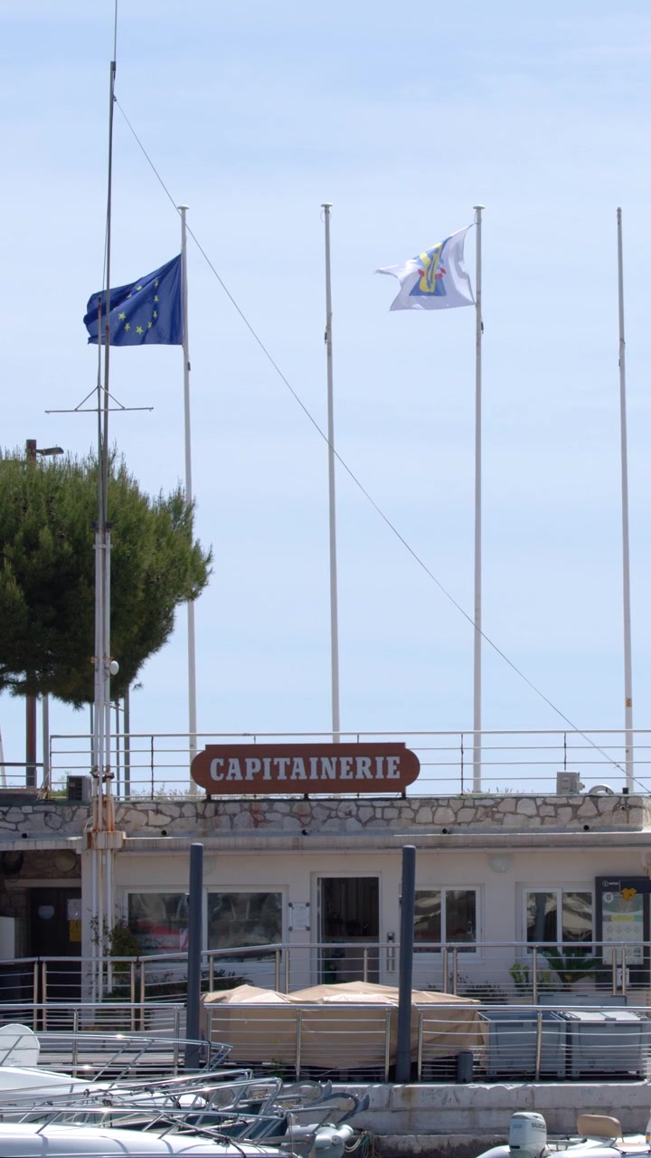 Bandiere dell'Unione Europea e locali sventolano sopra la capitaneria di porto a Cassis, Francia