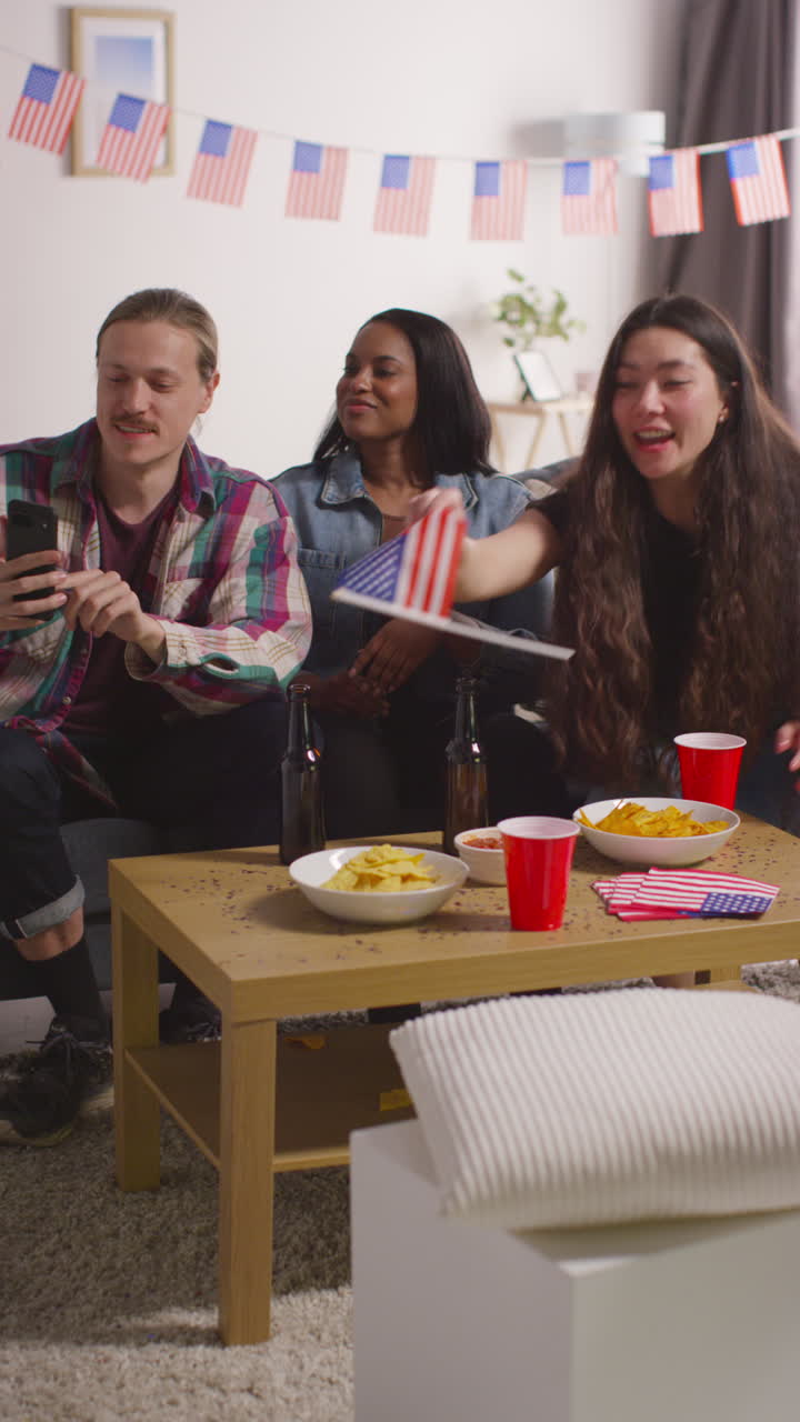 video vertical de amigos en casa celebrando con un partido el día de la independencia de estados unidos el 4 de julio haciendo una llamada de video en teléfono móvil
