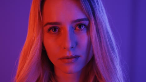 close up view of blonde young woman smiling cheerfully to the camera on violet background