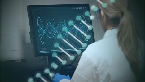 Animation-of-dna-strand-spinning-over-caucasian-female-scientist-using-computer