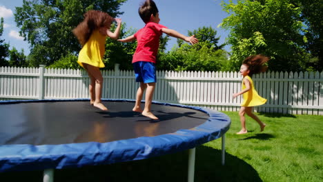 children playfully jumping and flipping on a trampoline in a sunny backyard