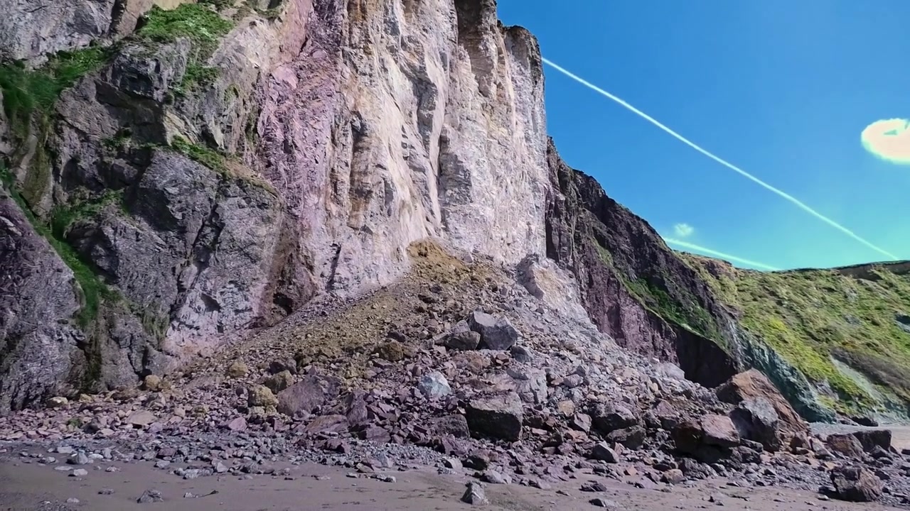 Rekaman panning ke atas erosi pantai yang menunjukkan runtuhnya tebing laut dramatis di Pesisir Irlandia Waterford, Lokasi Menakjubkan.