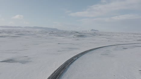 road traveling through frozen snowy tundra of iceland - aerial