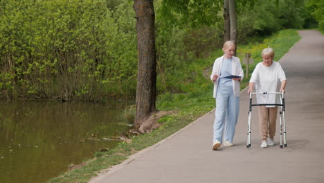 nurse assisting elderly woman in park