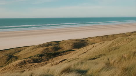 panoramic view of a serene sandy beach with dunes and ocean