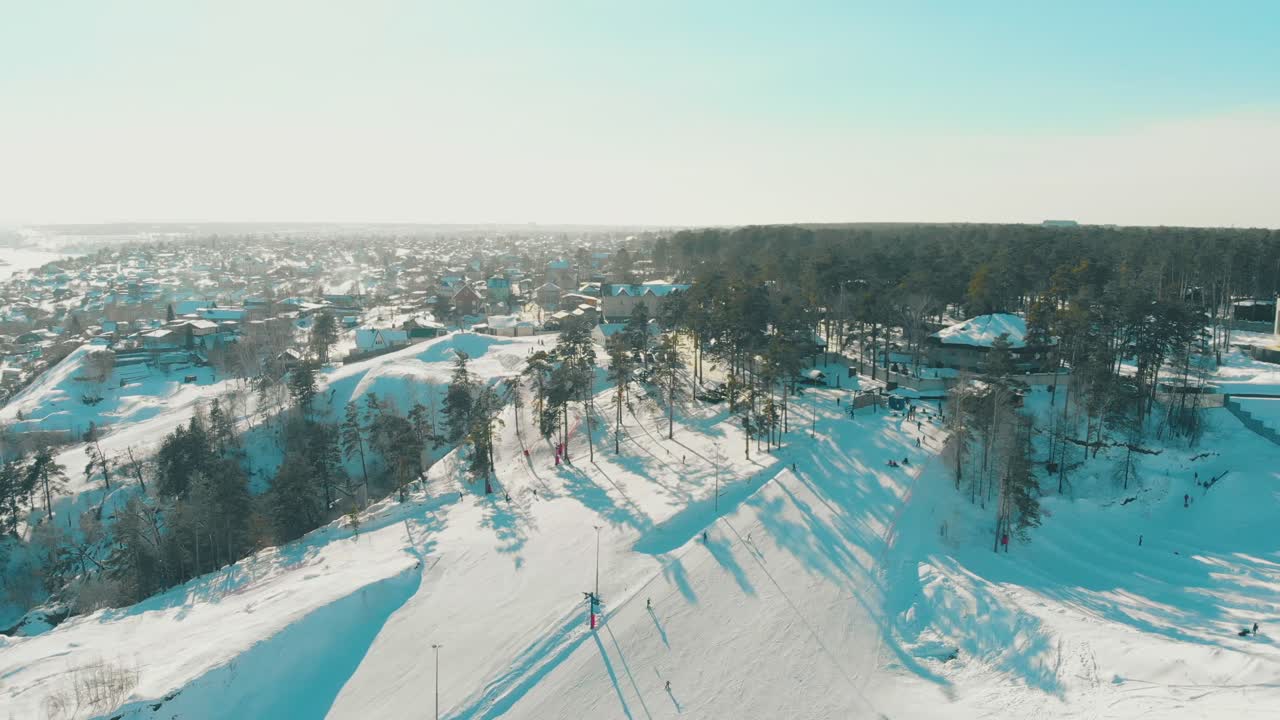사람들은 현대적인 눈 덮인 산 리조트 트랙에서 스키를 타요