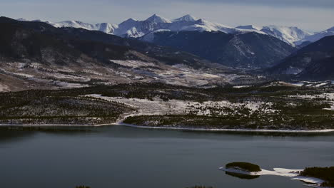 Downtown-Frisco-toward-Keystone-Colorado-aerial-cinematic-drone-Lake-Dillon-Marina-Summit-cove-cloudy-snowy-winter-morning-view-Silverthorne-Ten-Mile-Range-Breckenridge-calm-unfrozen-ice-right-circle