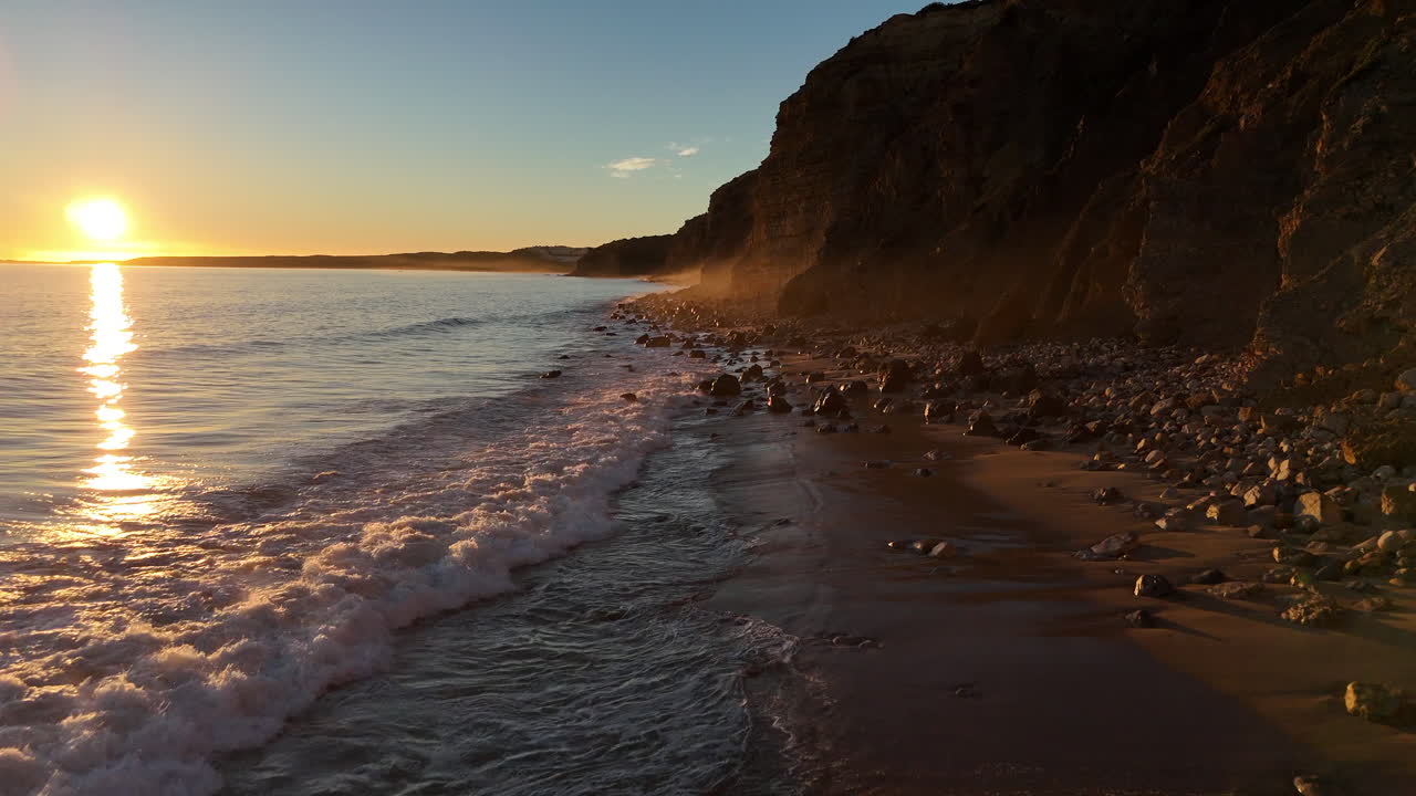 una ola rodando en una playa vacía al atardecer.