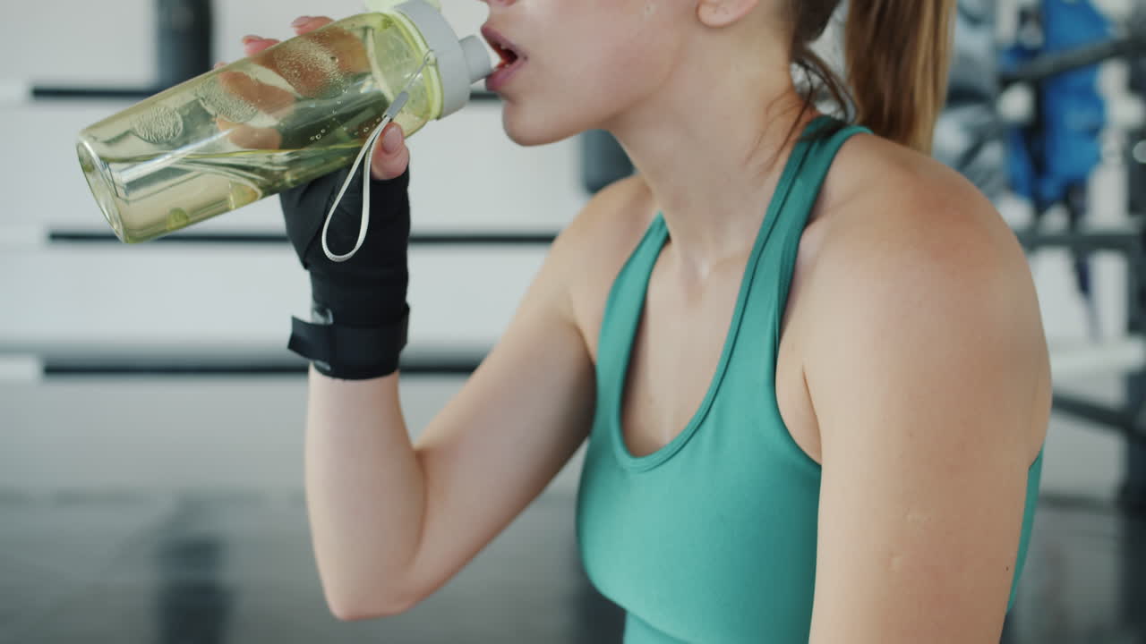 mujer bebiendo agua después del entrenamiento